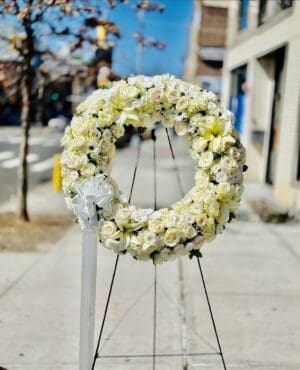 A GRACEFUL TRIBUTE WREATH on a stand displayed outdoors.