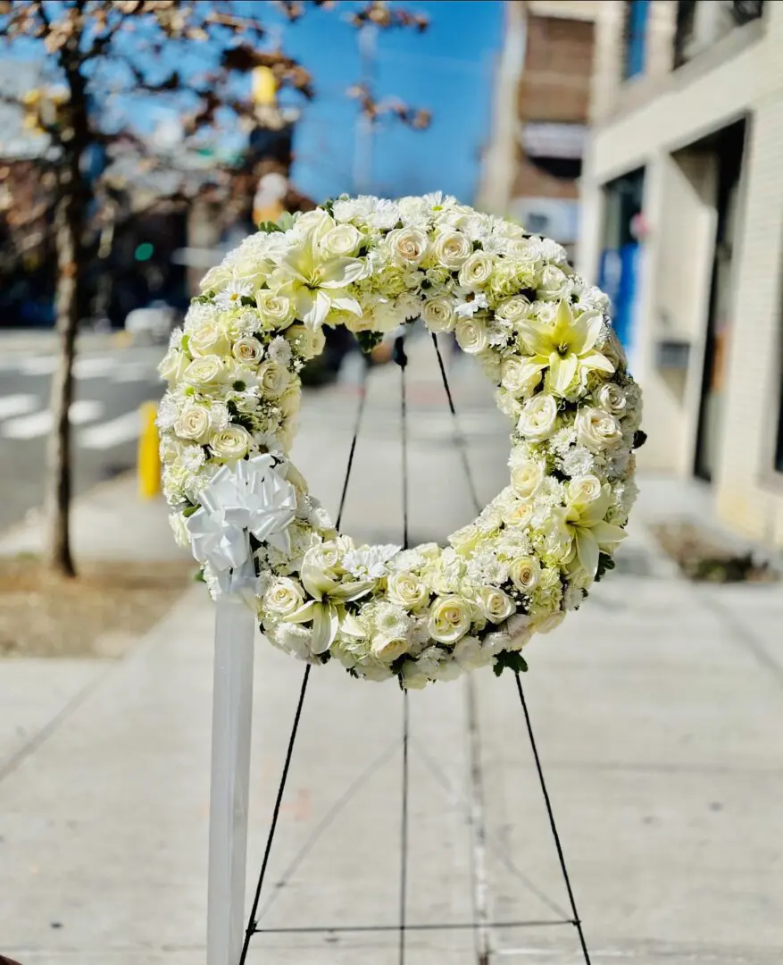 A GRACEFUL TRIBUTE WREATH on a stand displayed outdoors.