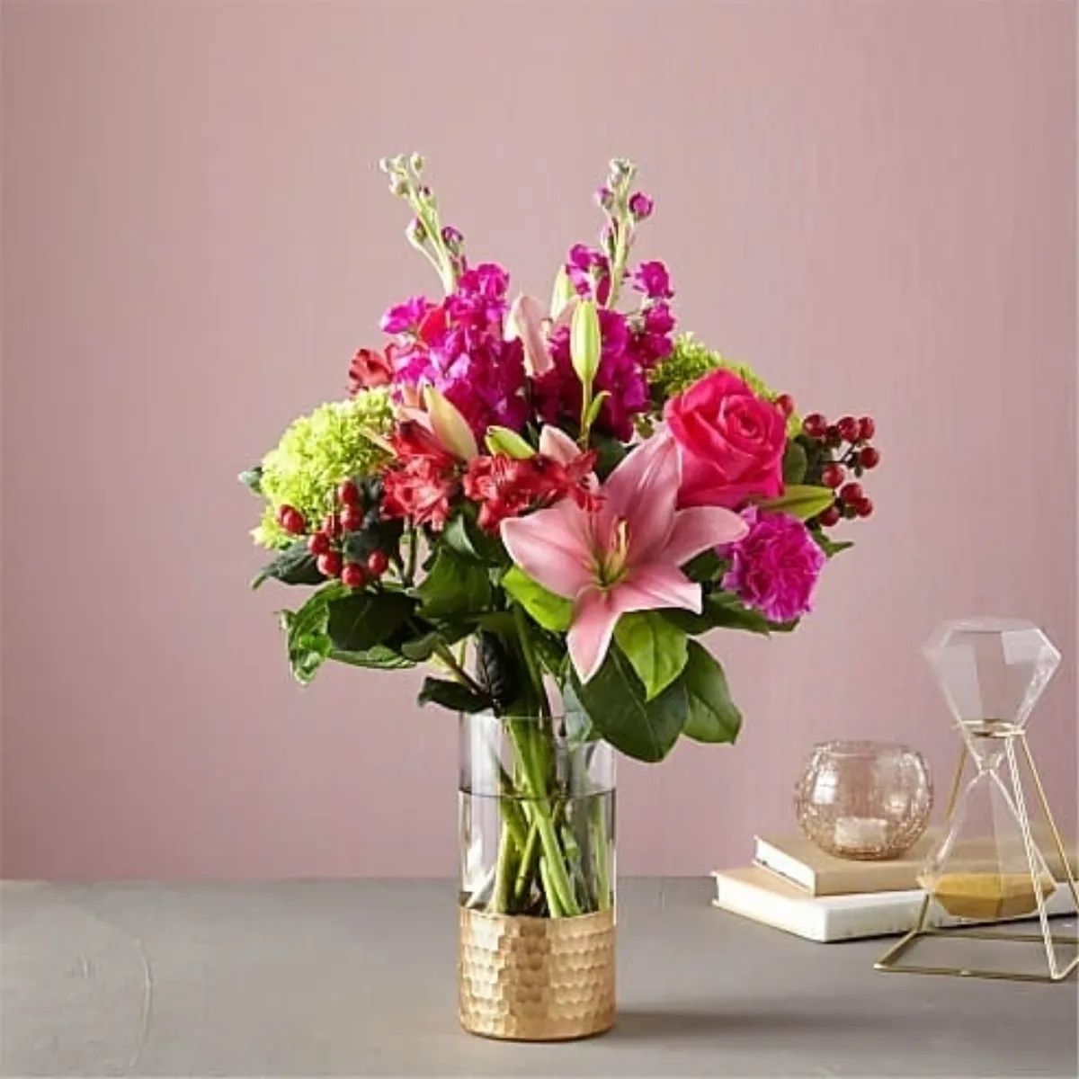 Assorted pink flowers in a tall glass vase