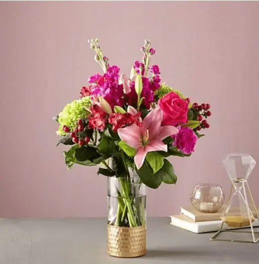 A glass vase with pink roses and lilies