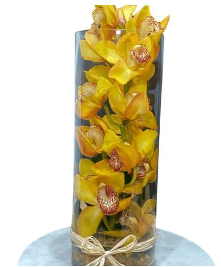 A glass vase full of yellow orchids