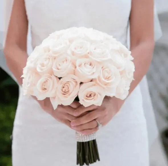 A bride holding a bouquet of light pink roses