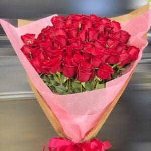 A bouquet of red roses wrapped in pink paper