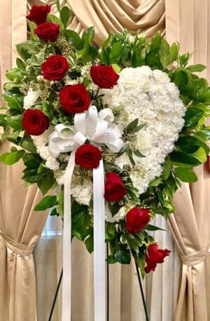 A heart-shaped wreath with white flowers and red roses