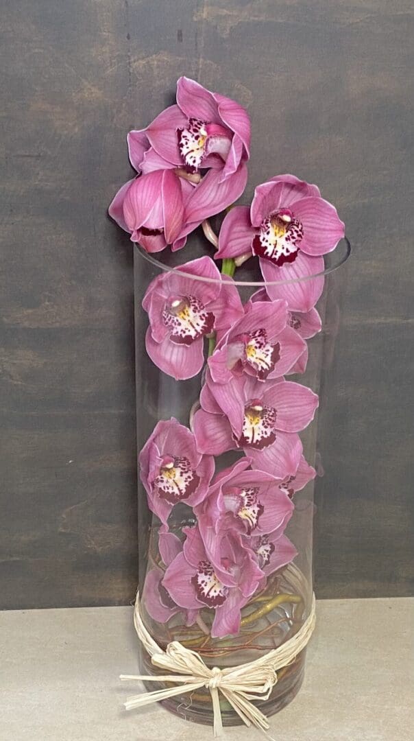 A tall glass vase with pink orchids