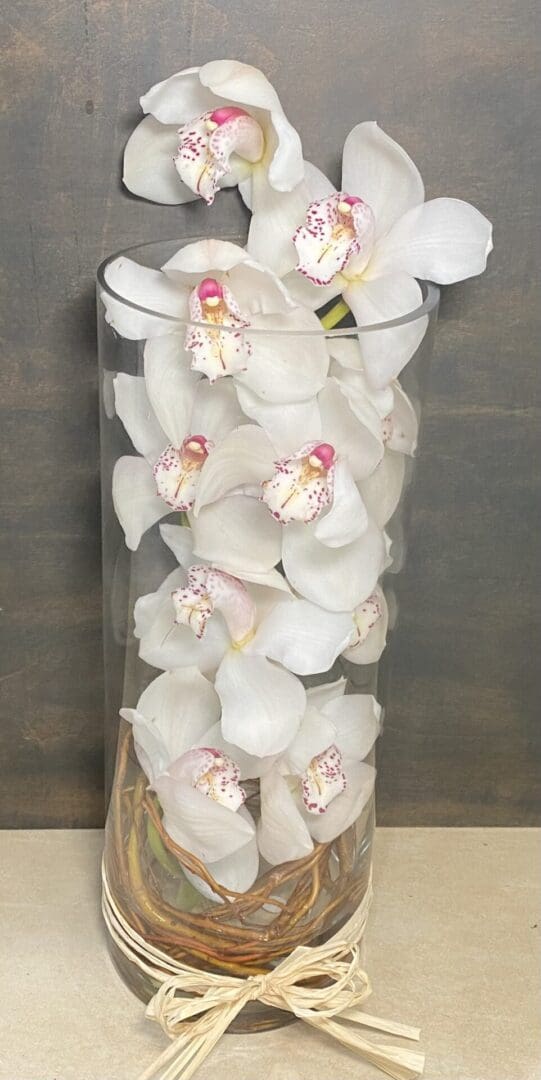 A tall glass vase full of white orchids