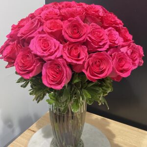 A glass vase with hot pink roses