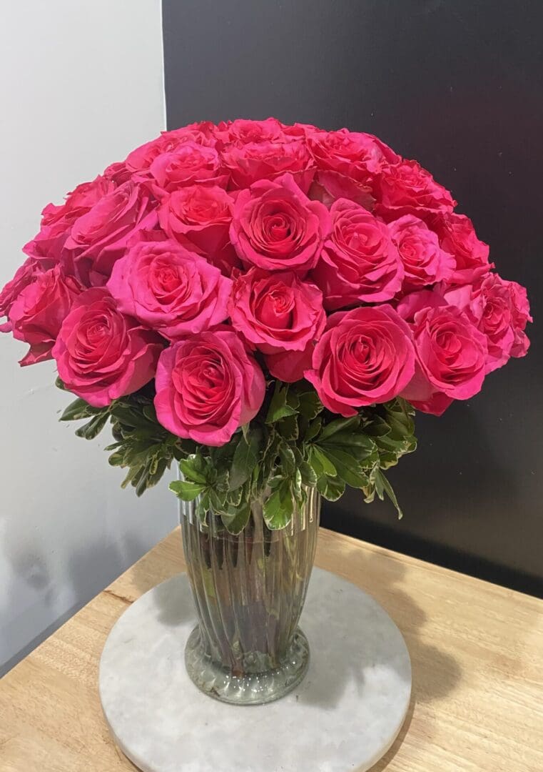 A glass vase with hot pink roses