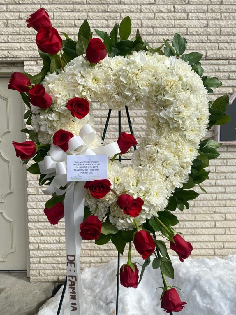 A heart-shaped wreath made of white flowers and red roses