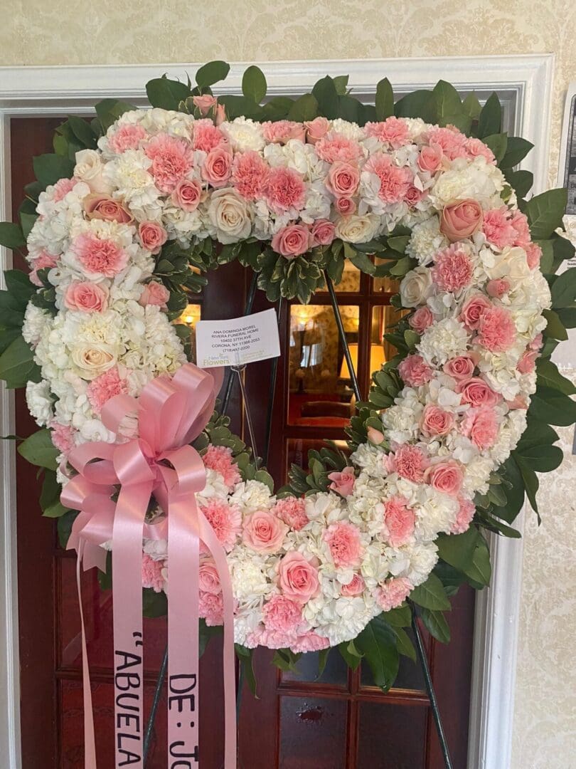 A heart-shaped wreath made of pink and white flowers