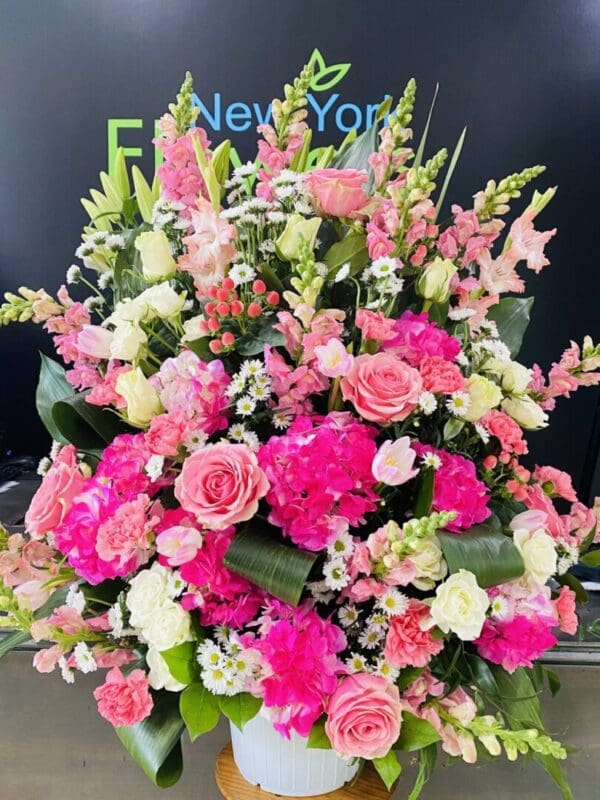 A white vase with assorted pink flowers