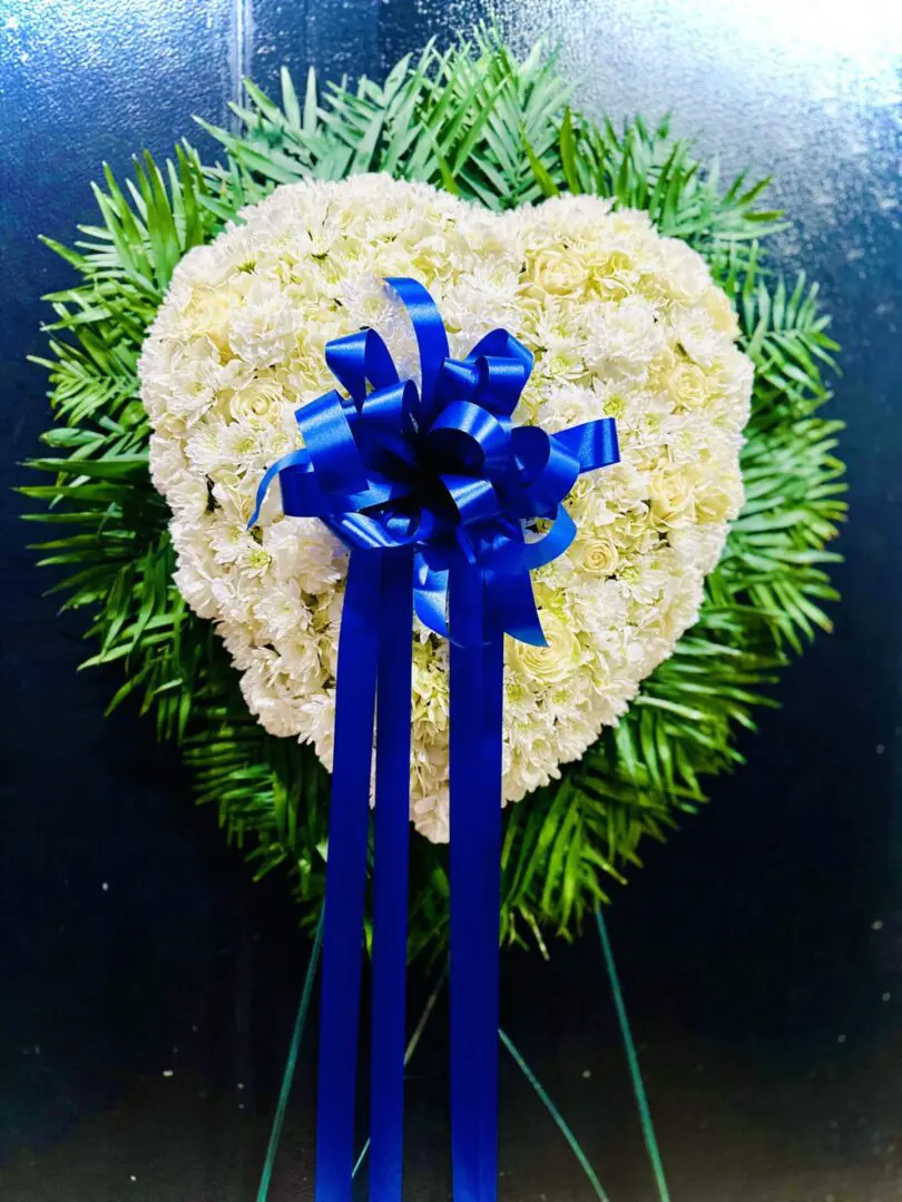 Heart-shaped floral arrangement with a BLUE AND WHITE SOLID HEART SYMPATHY ribbon.