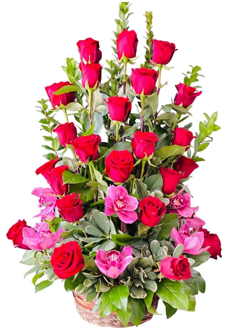 An arrangement of red roses and pink flowers in a basket.
