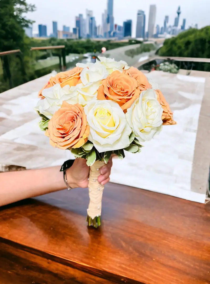 Person holding a bouquet of roses with a city skyline in the background.