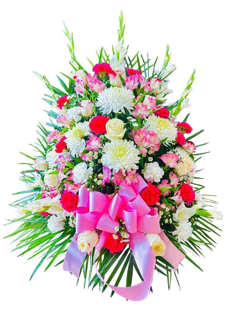 An elegant floral arrangement with a variety of flowers including roses and a prominent pink bow, isolated on a white background.
