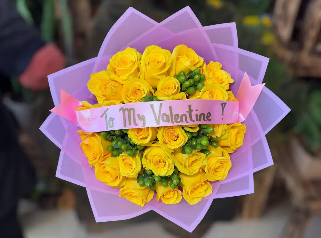 Sentence with product name: A 24 Yellow Roses Wrapped Bouquet with a ribbon reading "to my valentine".