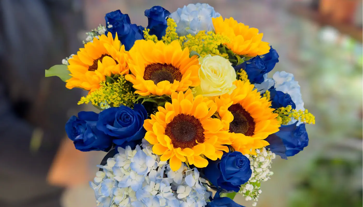 A vibrant bouquet featuring Sunflowers in the Sky, blue roses, and complementary floral fillers.