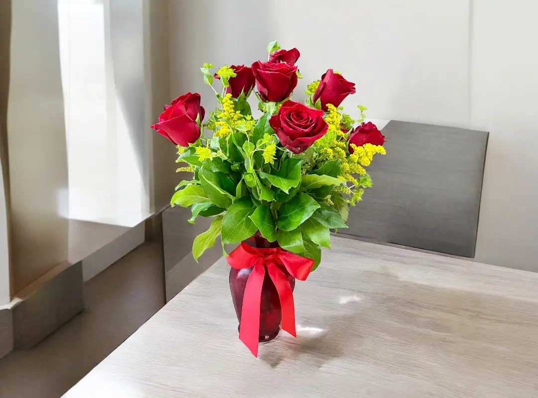 Red roses in a red vase with a bow.