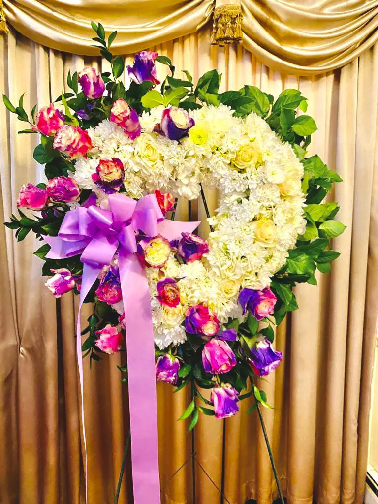 Floral wreath with pink and yellow blooms against a draped golden background.