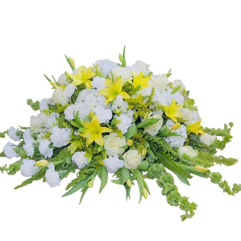 A White-Yellow Casket Spray with yellow lilies, white roses, and green foliage against a white background.