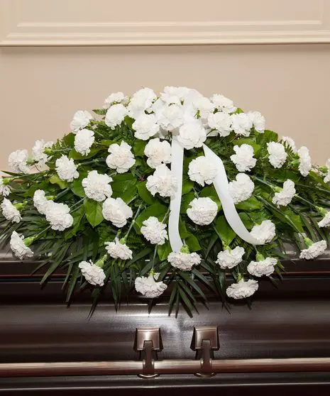 White Carnation Casket Spray on a casket at a funeral.