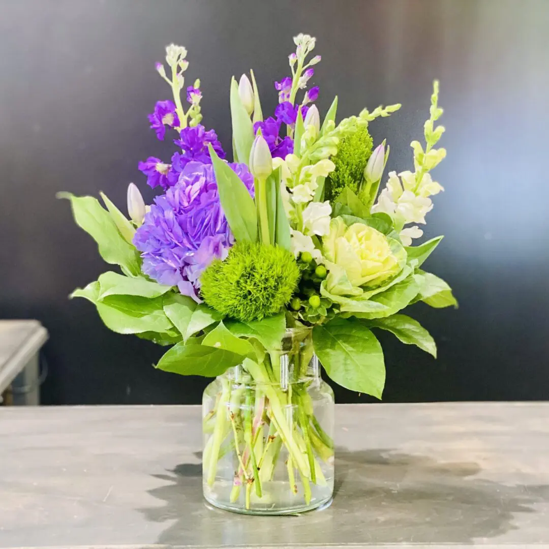 A vibrant bouquet of assorted flowers in a glass vase on a table.