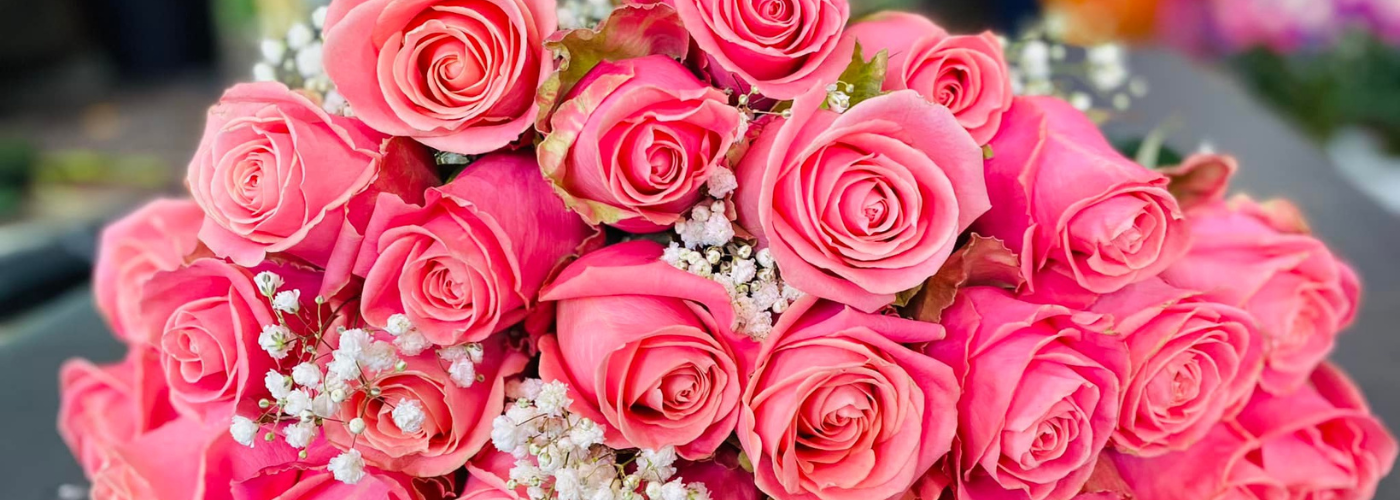 A vibrant bouquet of pink roses with interspersed baby's breath flowers.