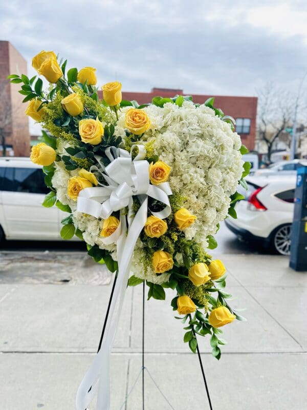 A White Standing Heart With Yellow Rose Break arrangement of flowers.