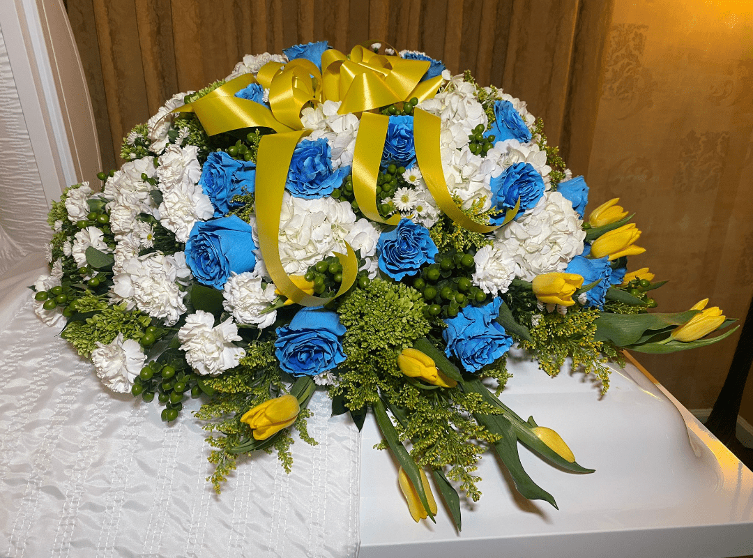 A large floral arrangement with blue and white flowers accented by yellow ribbons.