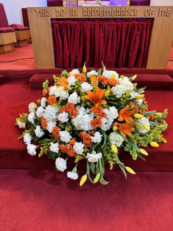 Floral arrangement on red carpet in church.