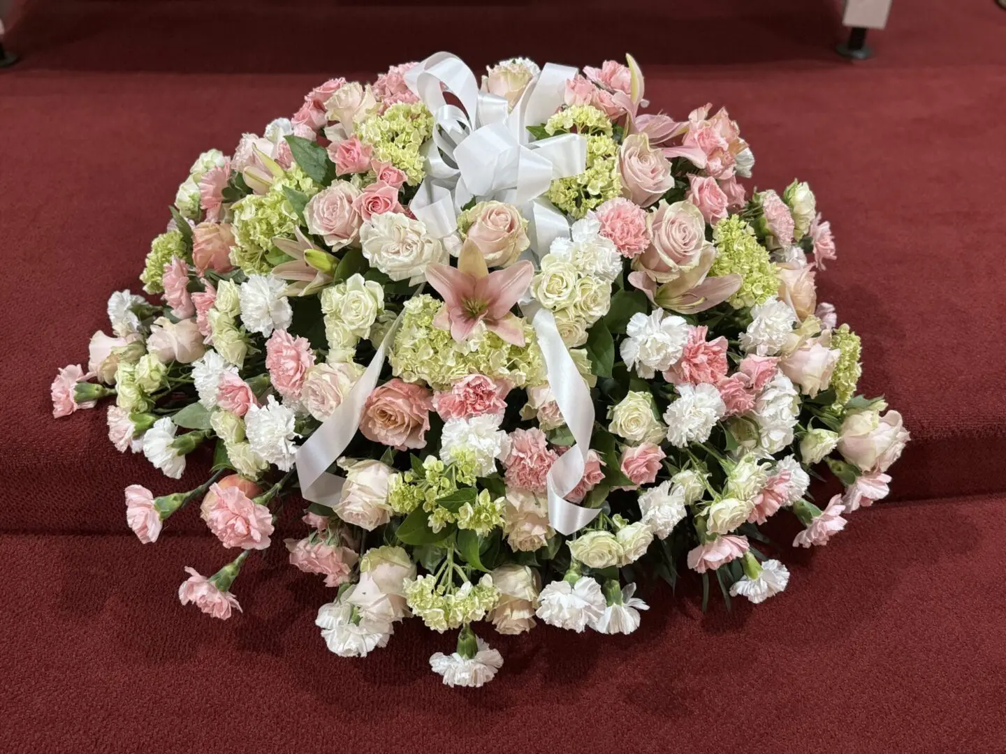 Pink and white flower arrangement on red carpet.