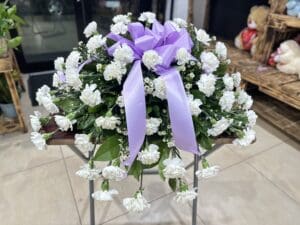 White carnation funeral arrangement with bow.